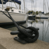 Black 12-strand HMPE rope tied around a stainless cleat on a boat in a marina.