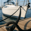 Black PA Pro Moor double braid mooring rope secured to a stainless steel cleat on a wooden dock, with boats in the background.