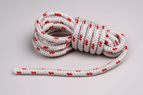 Coiled white double braid polyester sailing rope with red tracers displayed on a neutral background.