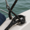 ropira-hmpe-sail-product-image 2 Black-and-orange HMPE double braid rope secured on a stainless steel cleat on a sailing boat.